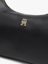 Cartera tipo hobo Tommy Hilfiger de acabado liso en color negro, con cierre de cremallera superior, asa corta de mano y correa tejida ajustable y extraíble en blanco y negro. Incluye detalle de logo metálico en relieve en la parte delantera y herrajes dorados.