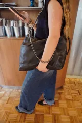 Cartera shopper grande de cuero negro con diseño acolchado en rombos y tiras de cadena metálica entrelazada con cuero.