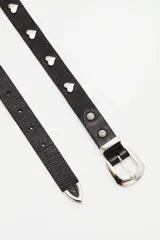 Cinturón de cuero vacuno negro con textura granulada, decorado con apliques metálicos en forma de corazón y hebilla metálica plateada.