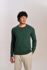 Sweater de punto fino color verde oscuro, con cuello redondo, mangas largas y puños y ruedo acanalados. Presenta un pequeño logo bordado en el pecho.