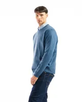 Buzo de punto liso color negro, con cuello redondo y puños y ruedo acanalados. Se lleva sobre una camisa celeste de vestir.