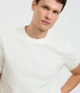 Remera color arena de corte regular, cuello redondo y manga corta. Tejido con textura vertical.