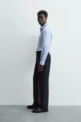 Camisa de manga larga, color blanco, con cuello italiano y corte slim fit. Presenta cierre frontal de botonadura y puños con botón.