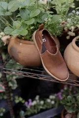 Zapatos tipo chelsea de cuero color marrón, con paneles elásticos laterales y suela plana de goma.