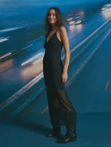 Vestido largo negro con escote en V, tirantes finos y falda transparente.