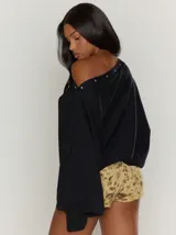 Sweater color crema con cuello asimétrico que puede usarse como escote off-shoulder, con botones a presión decorativos en el cuello y mangas abullonadas con puños acanalados.