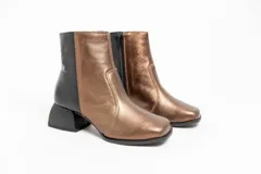 Bota corta de cuero color bronce, con detalle de cuero negro en el talón y taco geométrico.