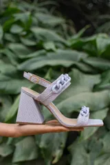 Sandalias de cuero con estampado de serpiente en tonos lila, con tira delantera y tira al tobillo adornadas con eslabones de cadena plástica al tono. Taco geométrico forrado en el mismo material.