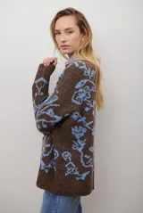 Buzo de tejido de punto en color marrón con un patrón ornamental floral en color celeste. Presenta cuello redondo, mangas largas y un corte holgado.