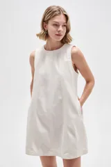 Vestido corto de jean blanco con tirantes anchos, cuello redondo, corte holgado y bolsillos laterales.