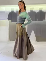 Falda larga plisada color marrón con estampado geométrico dorado en la parte superior y bolsillos laterales.