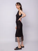 Vestido largo negro de tejido de punto con diseño de tramado y pequeños calados, sin mangas y con flecos en el ruedo.