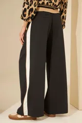 Pantalón negro de corte palazzo con cintura elástica y raya lateral blanca.