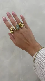 Anillo dorado con dos esferas de bronce.