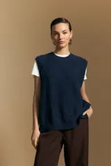 Chaleco tejido de punto en color azul marino, con diseño de textura sutil en relieve, escote redondo y terminaciones acanaladas en cuello, sisas y ruedo.