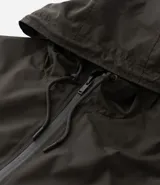 Campera rompevientos color tostado, con capucha ajustable mediante cordones, cierre frontal completo y puños elásticos. Presenta un diseño minimalista y funcional, ideal para protección contra el viento.