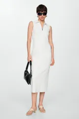 Vestido midi de tejido fluido y diseño entallado, color blanco, con cuello de solapa y cierre frontal de cremallera. Modelo sin mangas.