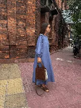 Vestido midi de corte holgado en color verde oliva, con mangas largas abullonadas que presentan detalles de volados en los hombros y puños elásticos.