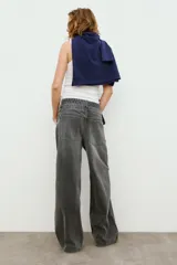 Jeans de tiro medio con cinco bolsillos, cintura doble a contraste y detalles de rotos. Cierre frontal con cremallera y botones metálicos.