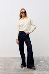 Sweater de punto color crudo, con cuello polo y cierre frontal de tres botones en tono carey. De manga larga y diseño holgado.