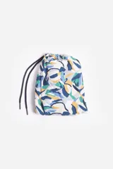 Short de baño celeste con estampado de hojas pequeñas en tonos verdes y blancos. Cuenta con cintura elástica con cordón ajustable, bolsillos laterales y un parche circular con logo en la parte inferior.
