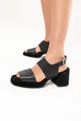 Sandalias negras de cuero con plataforma y taco cuadrado forrado. Presentan doble tira ancha sobre el empeine y tira con hebilla al tobillo.