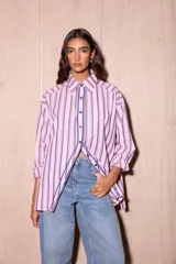 Camisa holgada de popelina de algodón a rayas verticales rosas, grises y azules. Presenta una abertura frontal con ribete festoneado en color azul marino y botones oscuros.