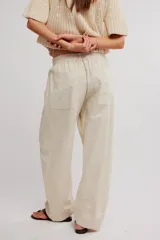 Pantalon de lino y algodon color beige, de tiro bajo, estilo relajado con cintura elastizada ajustable mediante cordón y bolsillos laterales.