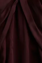 Blusa de satén color borgoña con mangas globo largas y puños anchos. Presenta un detalle de drapeado o nudo en el centro del escote redondo.