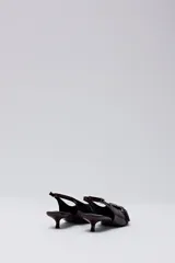 Zapato tipo slingback en color bordó, con punta fina, taco bajo y detalle de tira con hebilla metálica sobre el empeine.