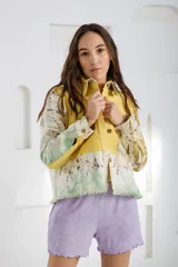 Chaqueta color beige con estampado abstracto en tonos amarillos, con cuello camisero, cierre frontal con botones, bolsillos plaqué y puños camiseros.