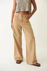 Pantalón jean color arena, de corte ancho y tiro bajo, con efecto desgastado.