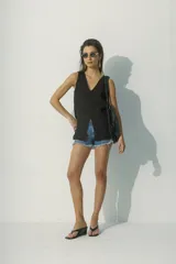 Blusa blanca sin mangas con escote en V y abertura frontal.
