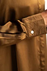 Camisa de satén color arena, de corte clásico con cuello camisero, manga larga con puños abotonados y detalle de encaje en el ruedo.
