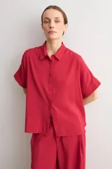 Camisa de manga corta color rojo, de corte holgado, con cuello camisero clásico y cierre frontal abotonado.