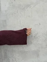 Polera de punto color bordó, con cuello alto abierto lateralmente, mangas largas amplias y corte recto.