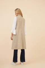 Chaleco largo color marrón claro, abierto, con lazo en la delantera y bolsillos ojal. Confeccionado en lana fina sin teñir.