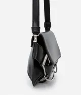 Cartera tipo baguette de tamaño pequeño, confeccionada en poliuretano color negro. Presenta una solapa frontal con detalles de hebillas metálicas decorativas en los laterales y un asa de hombro ajustable.