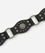 Cinturón negro de cuero sintético (PU) con hebilla grande redonda de metal plateado con diseño floral o de flor.