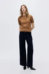 Sweater de punto suave con ajuste entallado, cuello redondo y mangas cortas. Presenta terminaciones acanaladas en cuello, puños y bajo.