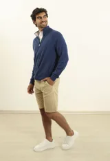 Cardigan azul de tejido de punto con cierre frontal, cuello alto y bolsillos laterales.