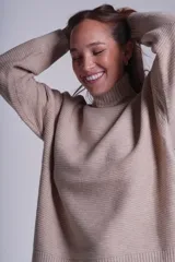 Sweater tejido de punto color beige, con cuello alto y trama lineal.