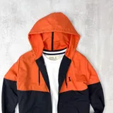 Campera de nylon impermeable con capucha, color naranja en la parte superior y negro en la parte inferior.