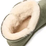 Bota corta de estilo invernal con acabado tipo gamuza en color verde. Presenta un diseño con forro interno de piel sintética, cierre lateral con botón de madera y suela de goma dentada.