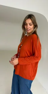 Sweater de tejido de punto color naranja oscuro, con cuello redondo, mangas largas y diseño holgado con caída fluida.