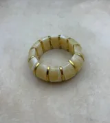 Pulsera elástica de diseño modular compuesta por piezas de resina con efecto marmolado y separadores metálicos dorados.