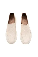 Zapatillas estilo náutico slip-on color off-white, confeccionadas en cuero vacuno con textura delicada y acabado nacarado. Cuentan con forro de cuero, inserciones elásticas laterales y una suela flexible y ligera con tecnología Antistress.