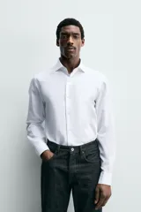 Camisa de corte regular fit confeccionada en tejido de algodón con textura. Presenta cuello italiano, manga larga con puños abotonados y cierre frontal de botones.