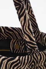 Cartera tipo mini tote con estampado animal print de cebra, confeccionada en algodón con relleno acolchado y doble asa de mano.