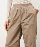 Pantalón deportivo de corte recto confeccionado en microfibra color marrón, con cintura elástica y recortes laterales en tule.